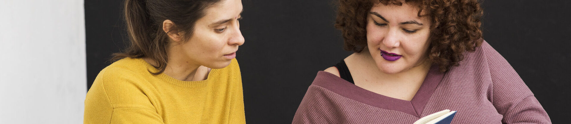 Zwei Frauen schauen gemeinsam in ein Buch.